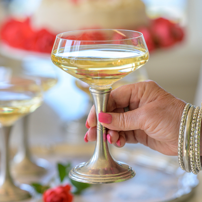 A close up photo of a woman holding a Verona coupe glass with pewter stem filled with sparkling wine
