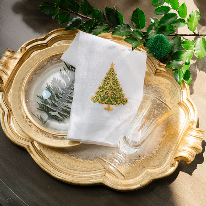 A gold Florentino tray with a Versailles Christmas tree embroidered white towel with Vetro Gold Flute and Plates on a table with Holly