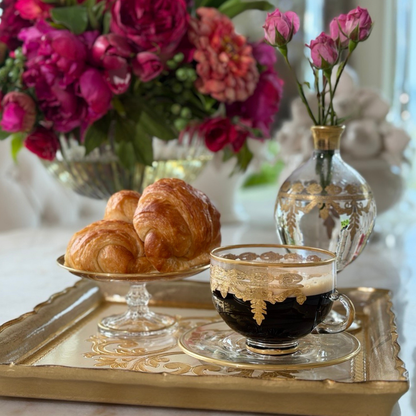 Croissants sitting on a Vetro gold patisserie dish on a Florentino Wooden tray with a Vetro Gold coffee cup and bud vase with pink flowers