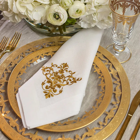 Vetro Gold Charger with a gold embroidered napkin with gold utensils and glassware with white floral arrangement