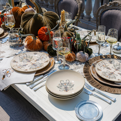 A stack of Villa pasta soup bowls on an outdoor table set with Villa plates, Velvet Pumpkins and Siena wine glasses