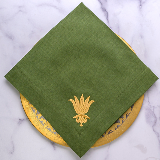 Evergreen linen napkin with a gold embroidered design on a Vetro Gold Plate.