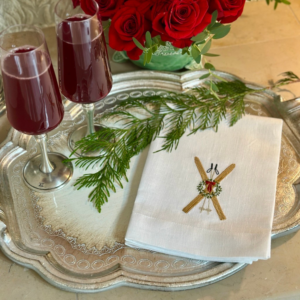 Napkin with embroidered vintage Ski design on a Florentino silver tray with Siena red wine glasses.