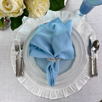 Washed Linen Napkin Set in light Blue in a crystal napkin ring on a stack of white plates - Arte Italica