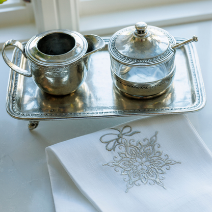 Anna caffe pewter tray with matching creamer and sugar on a white counter with embroidered snowflake linen towel