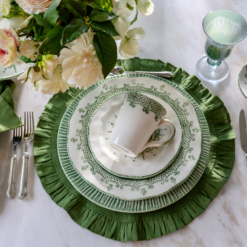Green Plates with a mug on a Evergreen Linen round Placement with Flowers on a Marble surface