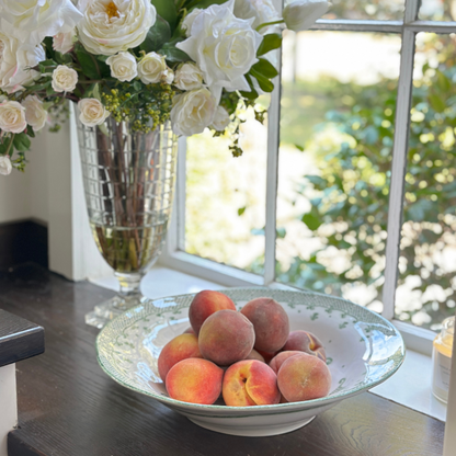 Arte Italica Burano pasta serving bowl green ceramic Italian hand painted dinnerware window sill view with flowers and full of peaches