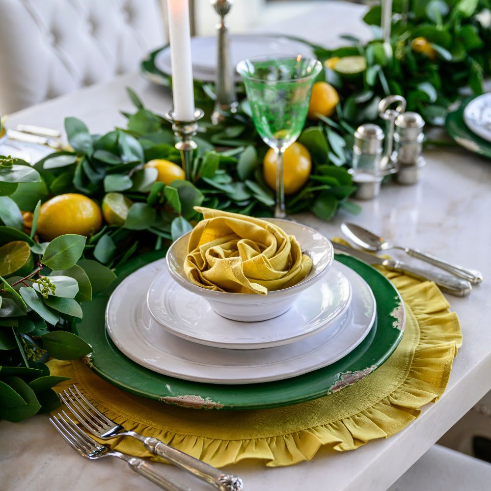 Elegant table setting with White Firenze Dinnerware with green and yellow accents, including lemons and silverware.