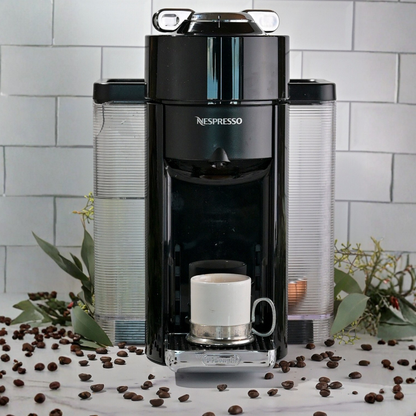 A coffee maker sitting on a white counter with a tuscan ceramic and pewter espresso cup 